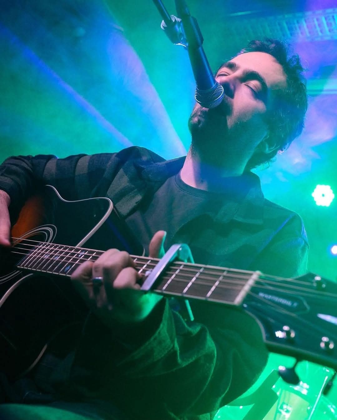 Ilko Birov performing with guitar under blue and green stage lights in Sofia